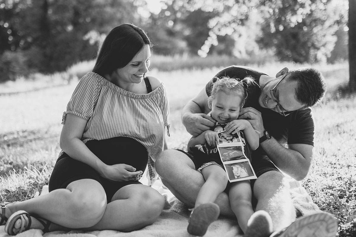 Familie mit Kleinkind und Ultraschallbild bei einem Babybauchshooting im Wald bei Wiener Neustadt.