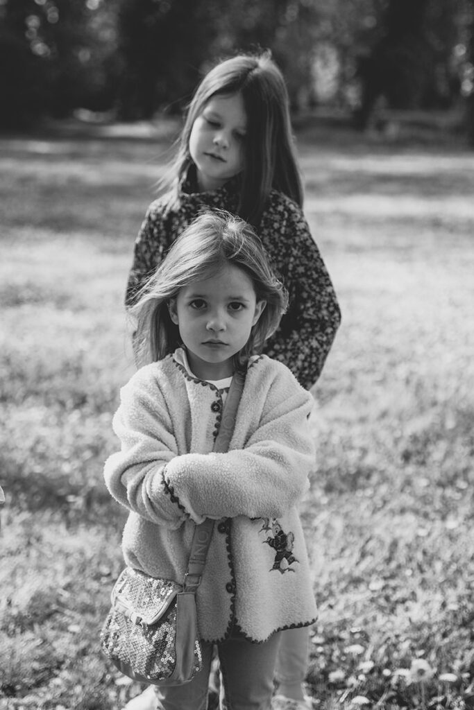 Kleine Schwester mit verschränkten Armen und entschlossenem Blick, Schwarz-Weiß.