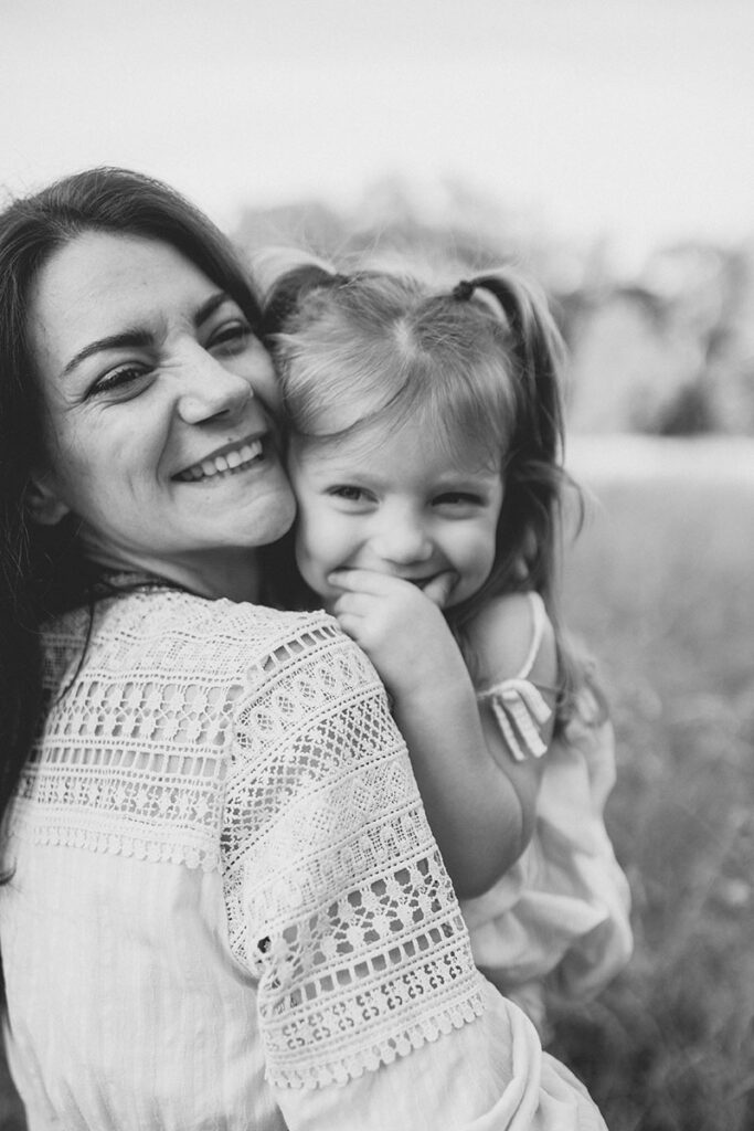 Kleinkind lächelt zufrieden im Arm der Mutter.