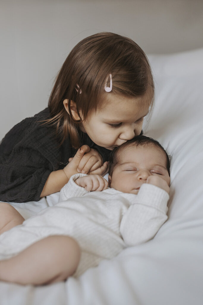 Newborn auf der Couch mit Schwester – echtes Familienleben beim Homeshooting