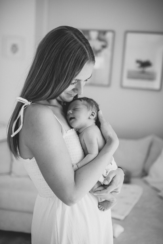 Mutter trägt ihr newborn durchs Wohnzimmer beim natürlichen Homeshooting