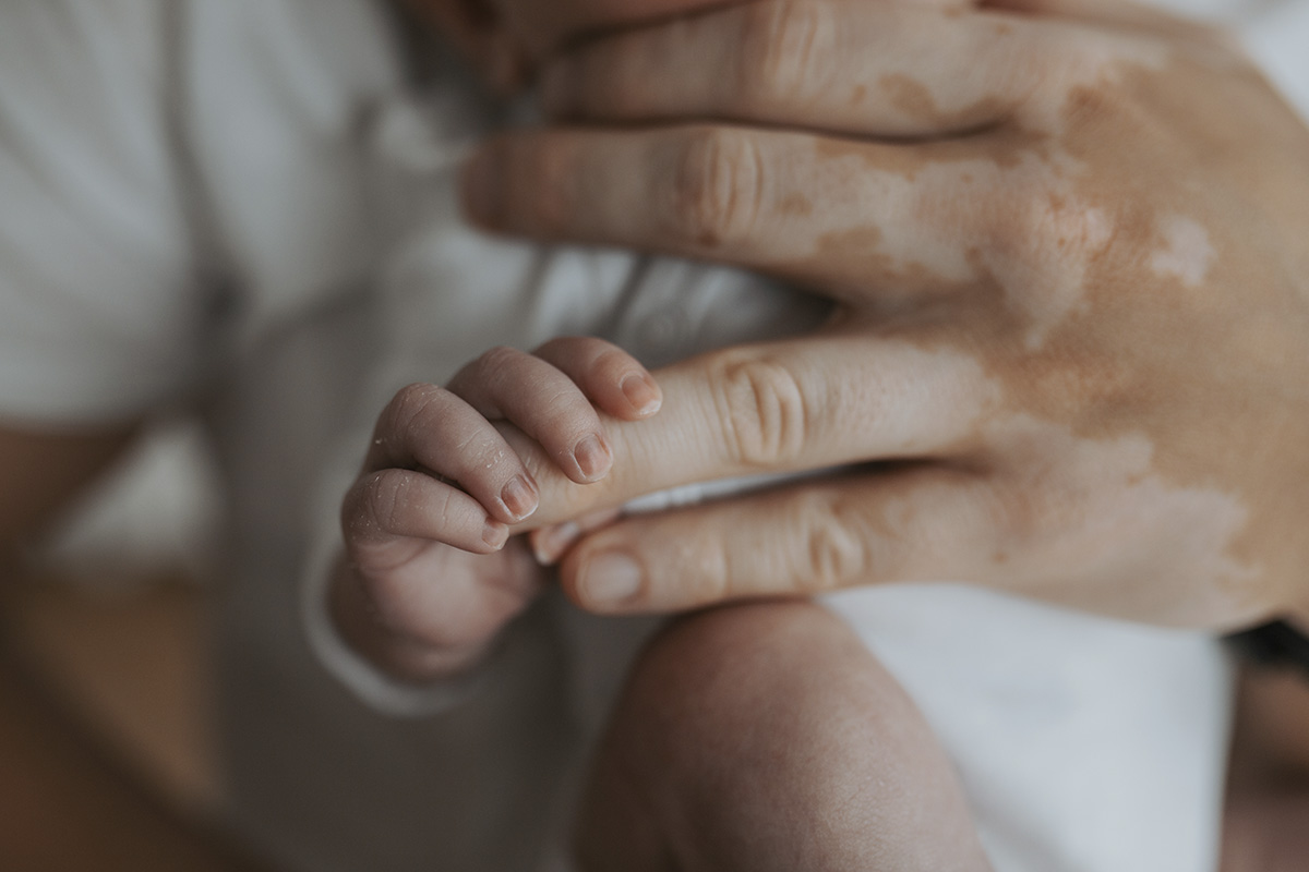 Babyhand greift nach Papas Finger – liebevolles Detailfoto in warmen Farben bei einem Homestory Shooting in Niederösterreich