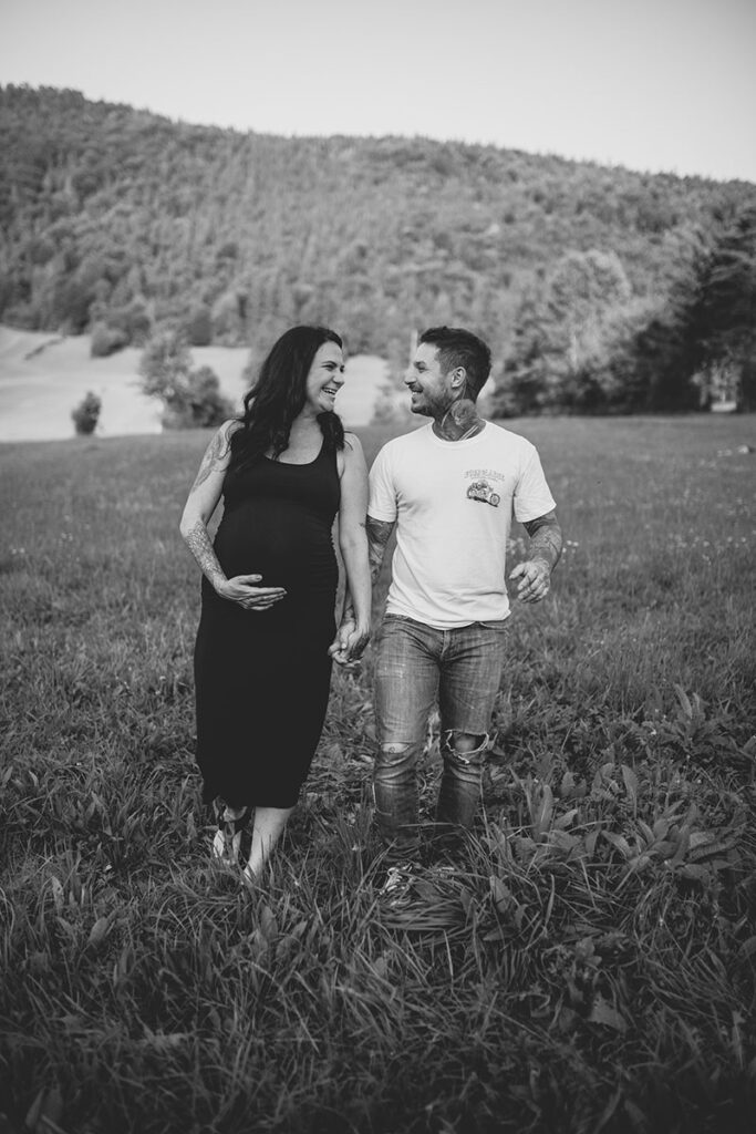 schwarzweissaufnahme-paar-babybauch-huegelige-landschaft