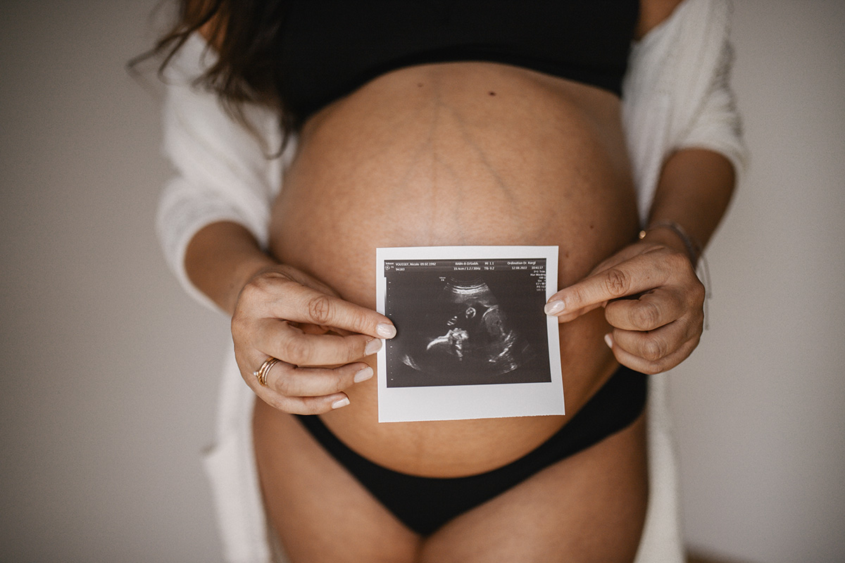 Ultraschallbild und Babybauch in warmer Lichtstimmung bei einer Homestory in Wr. Neustadt.